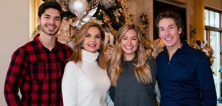 Alexandra Osteen smiling with her entire family during Christmas and wearing a dark-gray shirt.