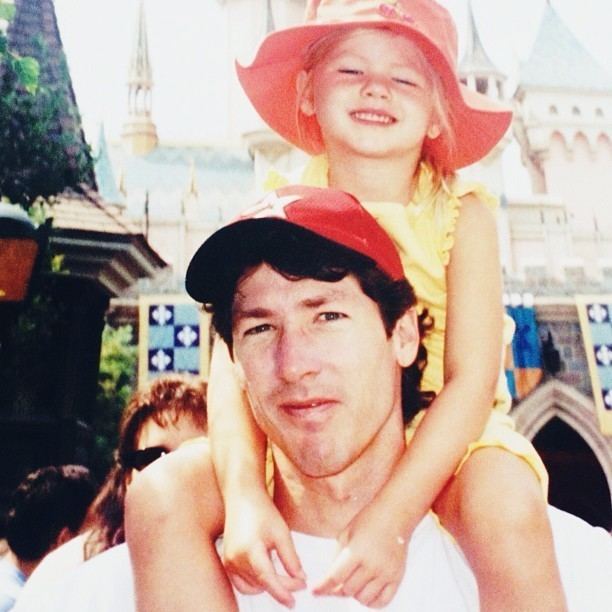 Alexandra Osteen as a child riding on the shoulders of her father, Joel Osteen and wearing yellow clothes and an orange hat.