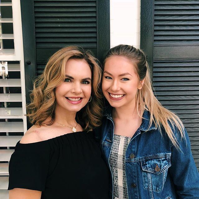 Alexandra Osteen smiling with her mother, Victoria Osteen, and wearing a jean jacket over a black and white shirt.
