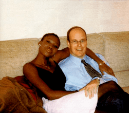 Nicole Coste wearing a black top and a white skirt while Prince Albert II wearing eyeglasses and blue long sleeves with a tie.