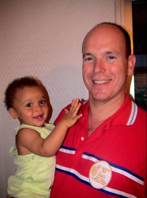 Alexandre Coste at a young age wearing a yellow shirt carried by his father Prince Albert II wearing a red polo shirt.