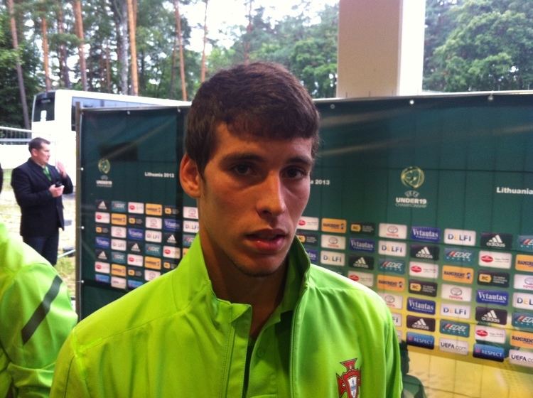 Alexandre Guedes looking serious while wearing a green shirt under a green jacket with a logo on it