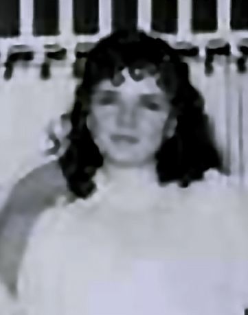 Alfreda Frances Bikowsky at a young age, wearing a white shirt with curly hair.