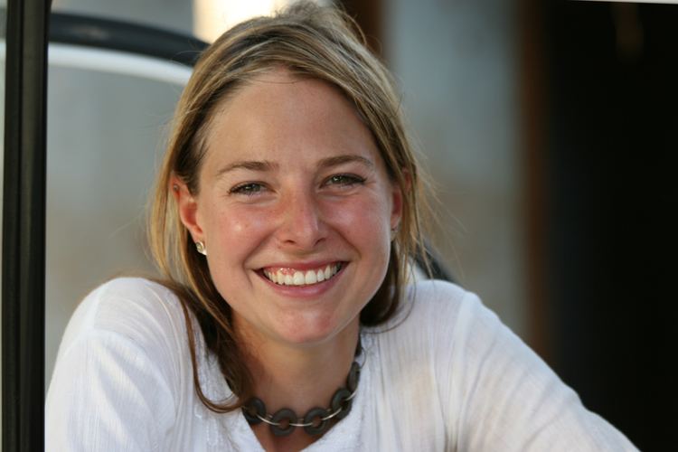 Smiling Alice Roberts wearing a white sleeve and necklace