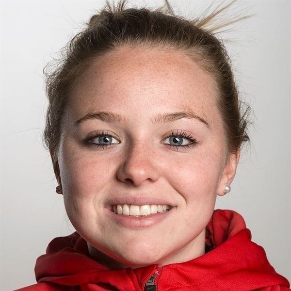 Alina Pätz smiling, wearing pearl earrings and a red jacket.