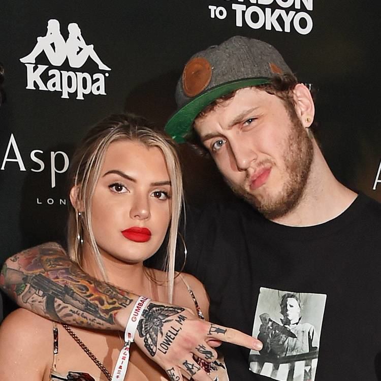 Alissa Violet and Faze Banks with intimidating faces. Alissa wearing hoop earrings, and a spaghetti top while Faze has tattoos on his arm, wearing a cap and black shirt.