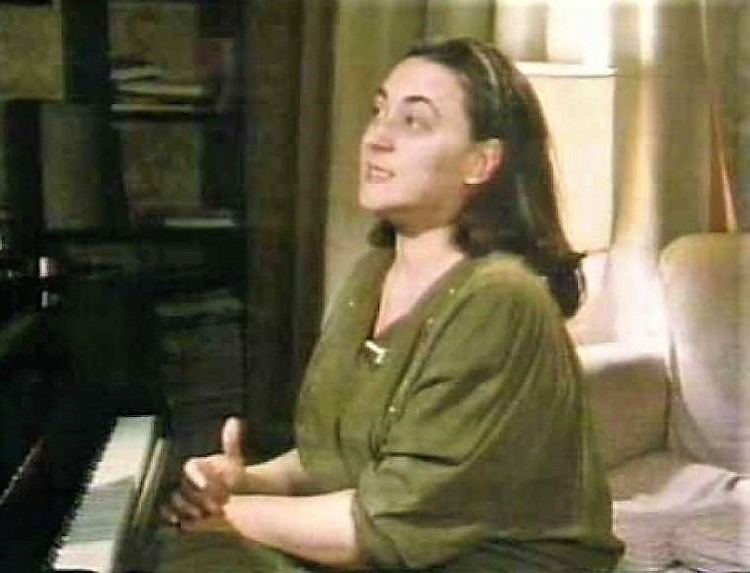 Aliza Kezeradze in front of a piano wearing a green shirt