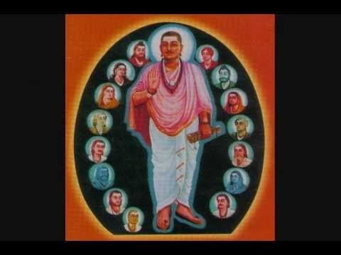 Allama Prabhu surrounded by a portrait of different people while wearing a pink top, necklace, and white pants