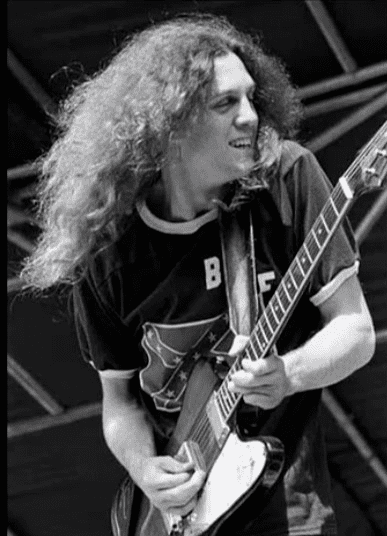 Allen Collins playing a guitar on stage while wearing a black shirt.