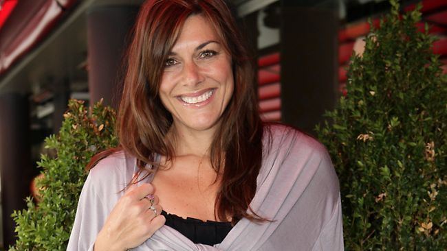 Ally Fowler smiling while wearing a gray blouse and black inner top