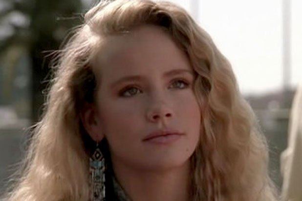 Amanda Peterson with a serious face, curly blonde hair, and wearing earrings.