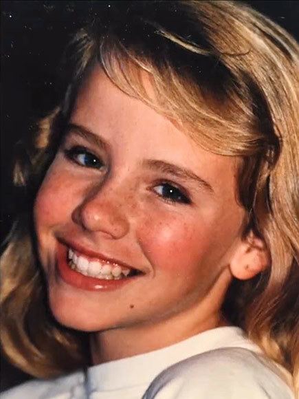 Young Amanda Peterson with a smiling face, blonde hair, and wearing a white shirt.