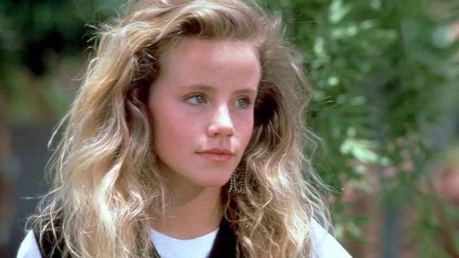 Amanda Peterson with a serious face, curly blonde hair, and wearing a white shirt.