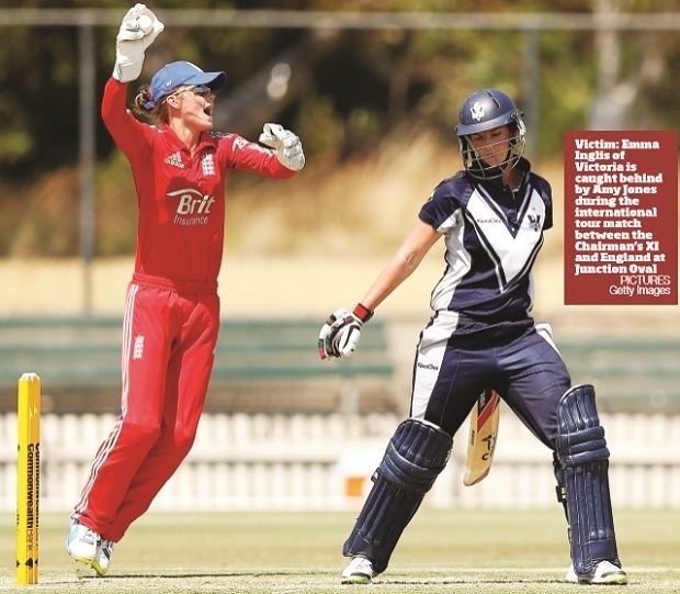 Amy Jones playing cricket while wearing a red long sleeves, red pants and blue cap