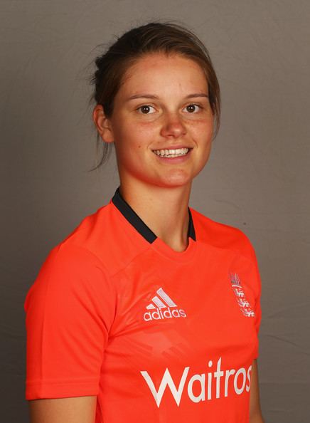 Amy Jones smiling while wearing a white and orange t-shirt