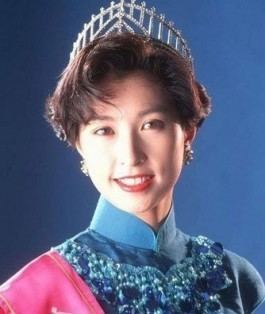 Amy Kwok smiling while wearing a crown, blue dress, and pink sash