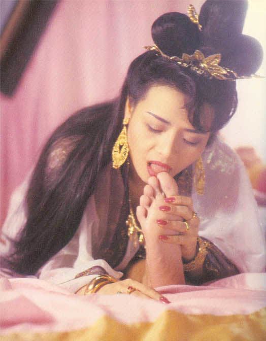 Amy Yip wearing gold jewelries and white dress while licking a foot