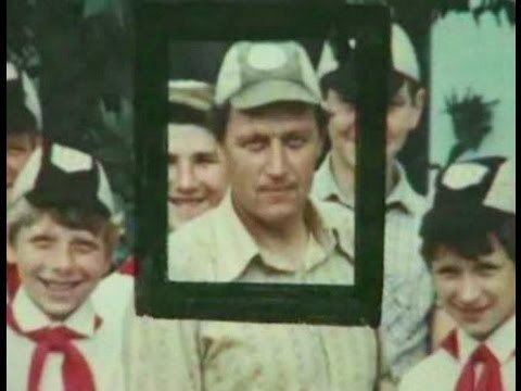 Anatoly Slivko smiling with the young boys and he is wearing a cap and striped long sleeves