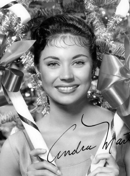 Andra Martin smiling while holding a striped stick with ribbon and wearing a sleeveless blouse