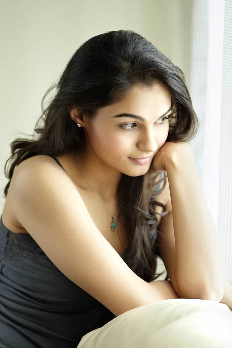 Andrea Jeremiah is serious, has long black hair, her left hand on her chin, wearing a silver necklace and diamond blue necklace, and a black sleeveless.