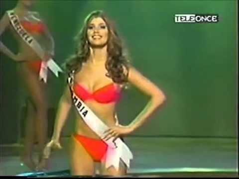 Andrea Nocetti smiling, wearing a red swimsuit and a sash during the Miss Universe beauty pageant.