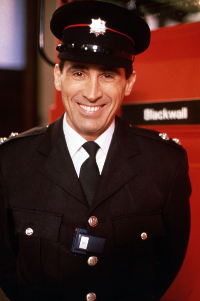 Andrew Kazamia smiling and wearing an officers attire as Nick 'Zorba' Georgiadis in the 1991 TV series London's Burning.