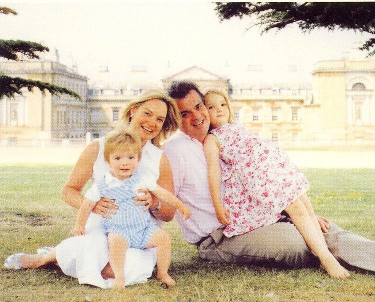 Andrew Russell, 15th Duke of Bedford, smiling with his family while sitting on the ground