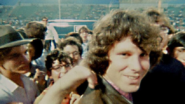 Jim Morrison smiling while surrounded by a crowd