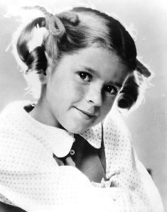 Anissa Jones in a black and white portrait sporting a two ears hairstyle and wearing a white dress.