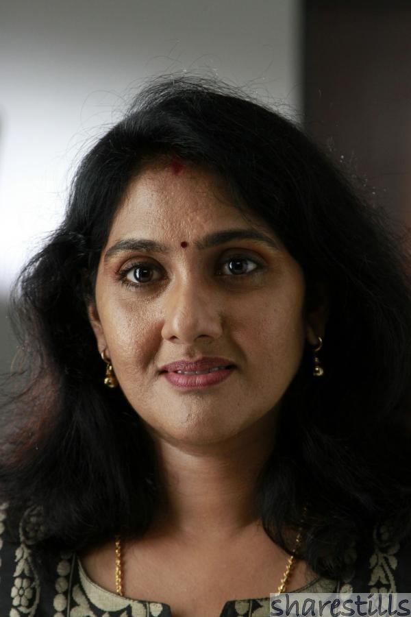Anju Aravind wearing a necklace and earrings with wavy black hair.