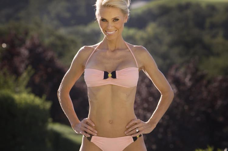 Anna Anka smiling while hands on her hips and wearing a pink and black bikini