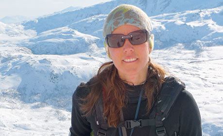 Anna Bågenholm smiles wearing a black long-sleeved shirt with thick snow in her background