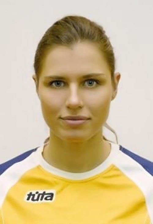 Anna Petrakova smiling with her hair tied wearing a shirt with shades of blue, white and yellow, and a logo