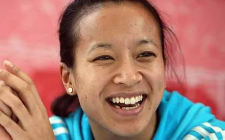 Anne Keothavong laughing while wearing a white and sky blue jacket and earrings