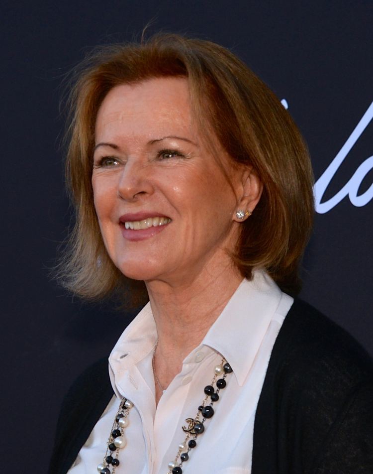 Anni-Frid Lyngstad smiling during the opening of ABBA: The Museum while wearing a black blazer, white inner blouse, and necklace
