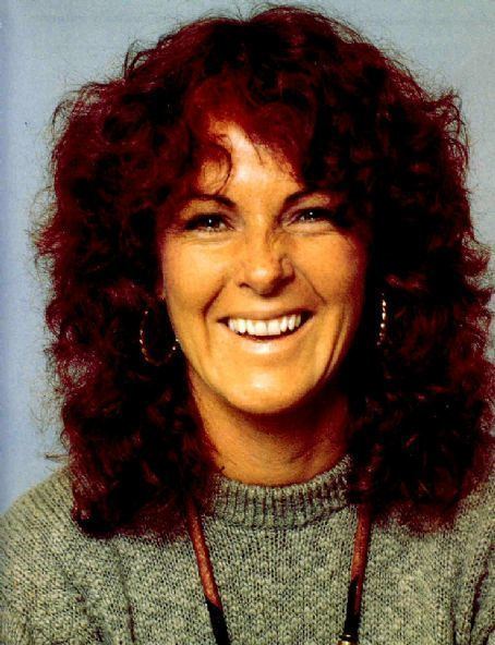 Anni-Frid Lyngstad smiling while wearing a gray knitted blouse and earrings
