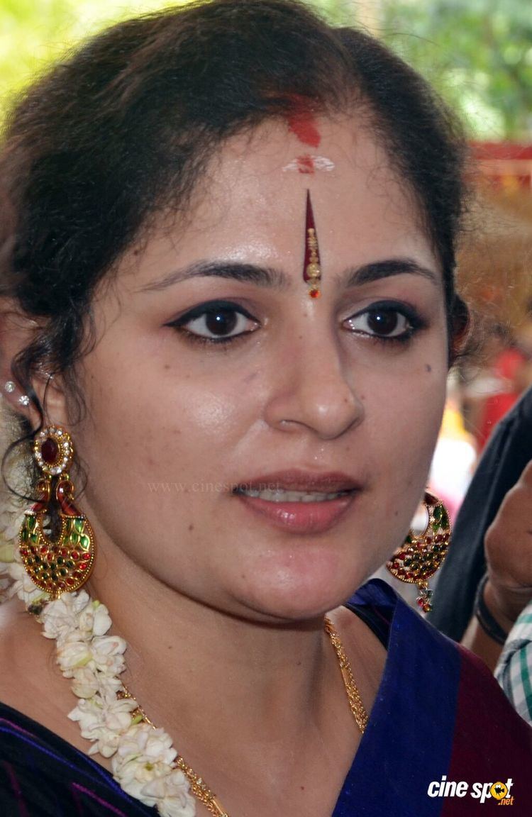 Annie with bindis on her forehead while wearing gajra, earrings, necklace, and black and blue dress