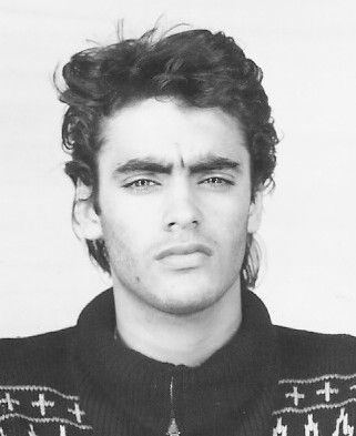Anthony Delon with a serious face while wearing a turtle-neck shirt with a cross design