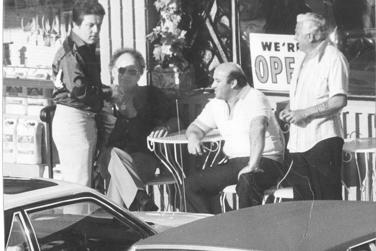 Anthony Spilotro wearing a black jacket and white pants together with his three friends outside the café.