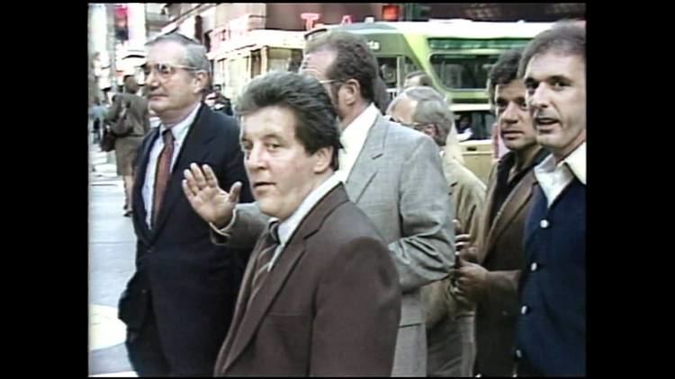 Anthony Spilotro wearing a suit and a striped tie surrounded by people.