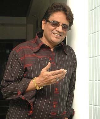 Anwar (singer) gesturing his right hand while smiling wearing a brown long-sleeved shirt