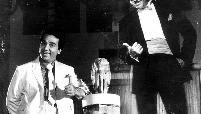 On the left, Kamal Haasan smiling while doing thumbs-up and leaning on an elephant statue, wearing a white coat, tie, and pants. On the right, Kamal Haasan doing thumbs-up, wearing a black coat, white long sleeves, and black pants.