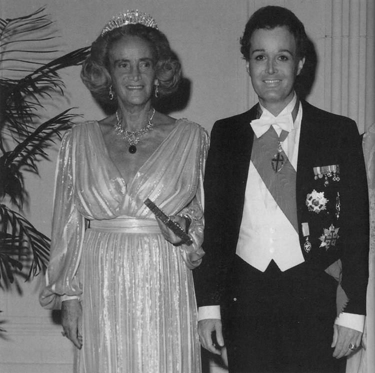 Arndt von Bohlen und Halbach posing with the Queen while wearing a royal outfit.