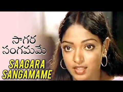 On the left is a word written in Telugu “SAAGARA SANGAMAME” on the right, Aruna Mucherla is serious, has black long hair, silver hoop earrings and white top.