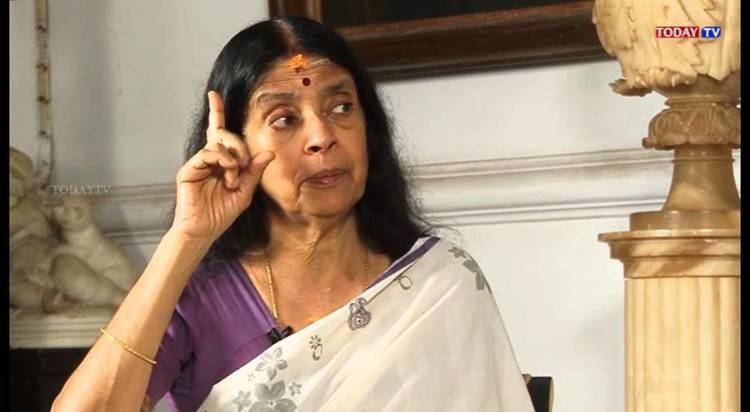 Aswathi Thirunal Gowri Lakshmi Bayi pointing her finger upward while wearing a white and violet dress