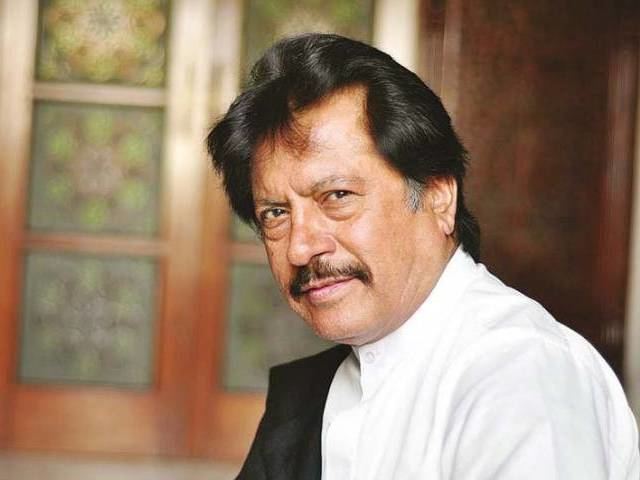 Attaullah Khan Esakhelvi with a tight-lipped smile while wearing a white long sleeves