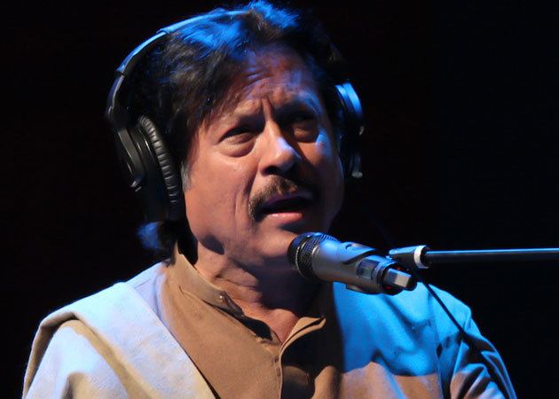 Attaullah Khan Esakhelvi singing while wearing a headphone and brown long sleeves