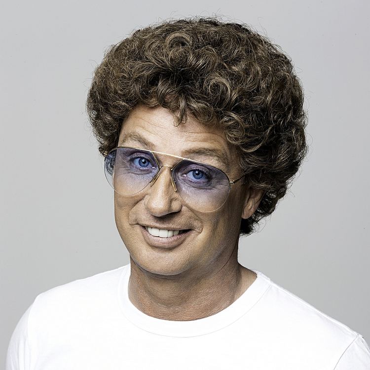 Atze Schröder in his unique hair, wearing a white shirt and a pair of glasses