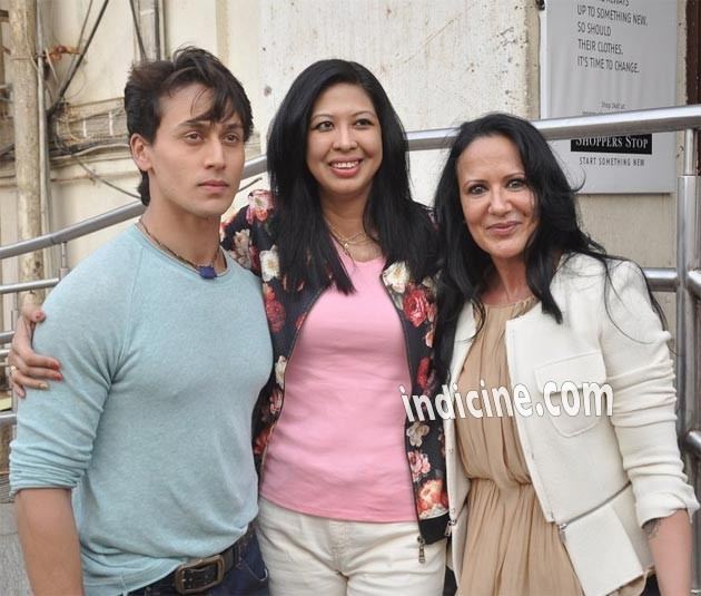 Tiger Shroff wearing gray sweatshirt with mother Ayesha Dutt wearing white coat and brown dress and the woman beside them wearing floral coat and pink inner top