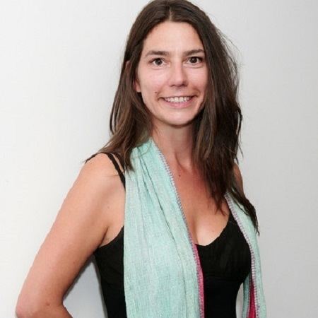 Ayisha Davies smiling while wearing a black sleeveless top and blue scarf